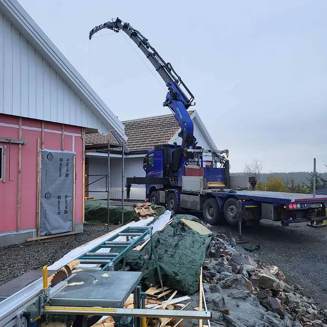 Lastebil med kran løfter materialer ved byggeplass